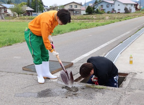 地域の方々と側溝の泥取りをする学生